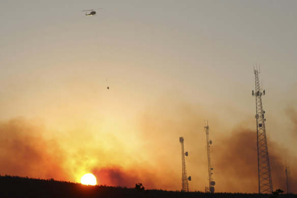 A helicopter carries water on a longline to a wildfire near Salem, Oregon.