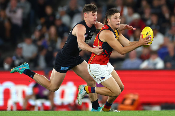 Jake Soligo of the Crows handballs whilst being tackled by Sam Walsh of the Blues.