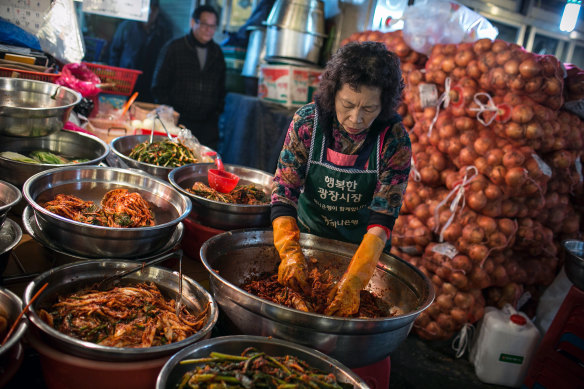 A merchant makes kimchi at a market in Seoul, South Korea. Kimchi is a traditional Korean dish of pickled vegetables served as a main or side dish. 