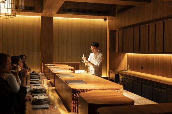 Chef Alex Yu pictured at work behind the counter, however large slabs of pink marble obscure the diner’s view, writes Besha Rodell.