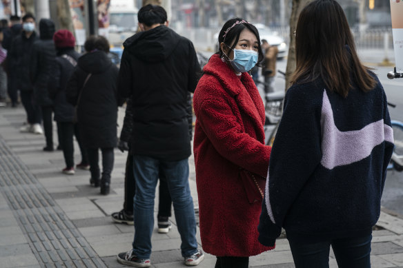Residents wear masks while queuing to buy milky tea in Wuhan on the first anniversary of lockdown.
