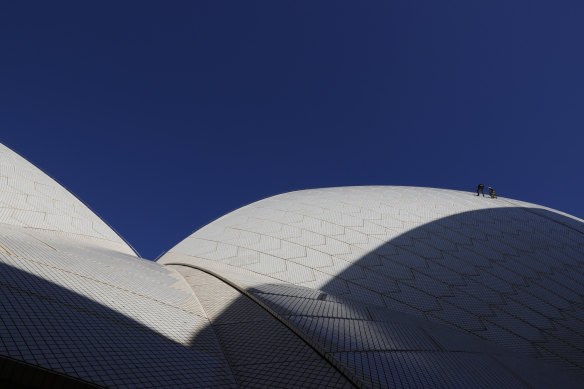 Sydney Opera House building operations manager Dean Jakubowski and height access specialist Dean Gillies work on the shell of the sails in the early morning light.