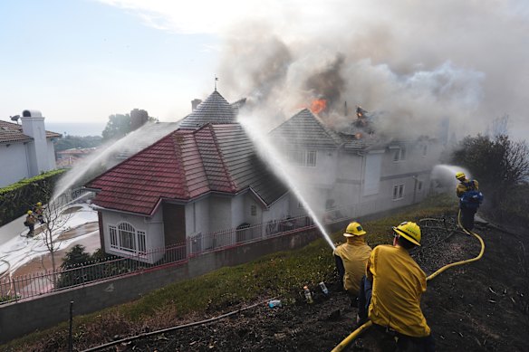 Firefighters work to douse a fire on house in flames during the Norte fire. 