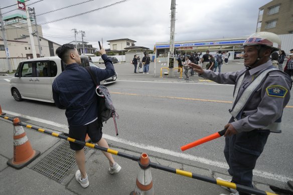 A security guard redirects a tourist outside of the construction site of a barricade near the Lawson convenience store.