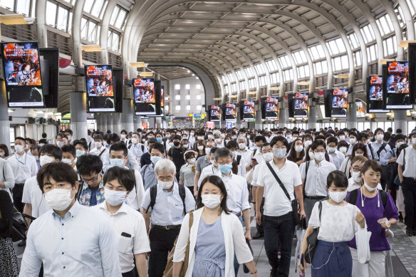 Commuters wearing face masks pass through Shinagawa train station in Tokyo.