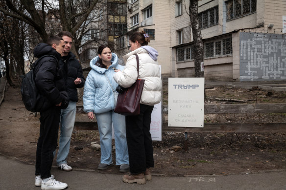 Students stop to chat near a sign promoting the nearby Trump Pizza Station in Kyiv, Ukraine.