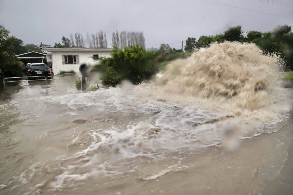 Water gushes from a storm drain access port on a street in Te Awanga, south-west of Napier, New Zealand.