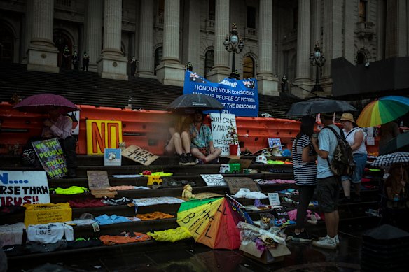 Protesters huddle under umbrellas as rain falls on Spring Street.