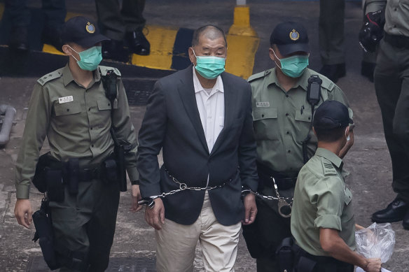 Hong Kong pro-democracy activist and media tycoon Jimmy Lai is escorted to a prison van before appearing in a court, in December.