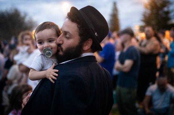 Rabino Yacov Harkham e seu filho, Ariel, abraçam-se entre milhares de pessoas durante uma vigília à luz de velas em Bondi Beach, em 21 de dezembro.