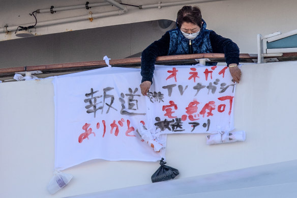 A passenger hangs a banner reading please broadcast this on TV next to a banner (L) reading thank you for reporting this on the Diamond Princess cruise ship at Daikoku Pier, in Yokohama, Japan.