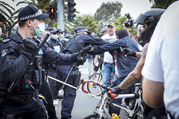 Dennis Basic in a balaclava clashes with police at a “Freedom Day” protest in Melbourne on October 23, 2020.