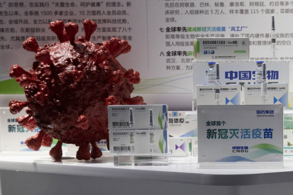 Samples of a COVID-19 vaccine produced by Sinopharm are displayed near a 3D model of the virus.