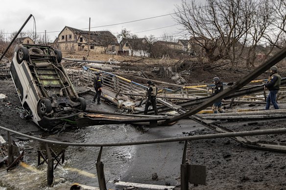 Members of the Ukrainian military walk across a destroyed bridge near the frontline amid fighting in Bucha and Irpin in Ukraine. 