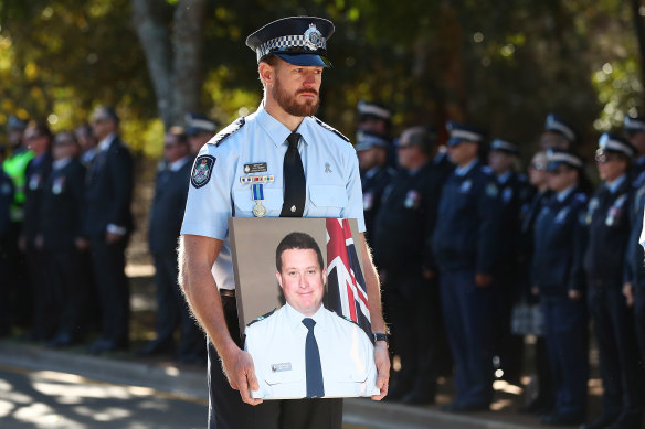 Sergeant Glen Thomas holds a photograph of Forte during the fallen officer’s funeral in Toowoomba.