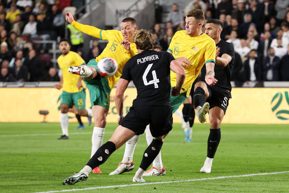 Mitch Duke unleashes the strike which led to Australia’s opening goal, ultimately awarded to Harry Souttar (right).