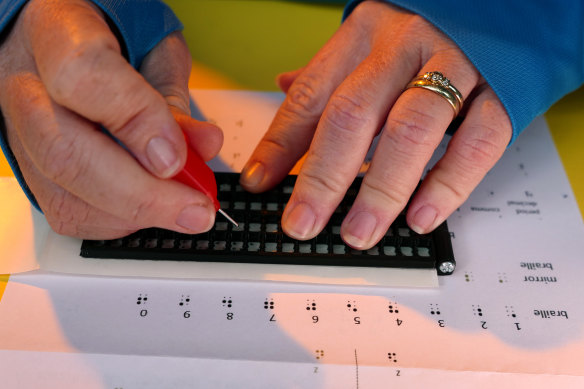 A “braille-bombing” participant writes their sign.