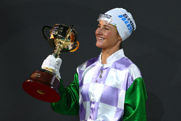 Michelle Payne carries her Melbourne Cup trophy out to the pool deck.