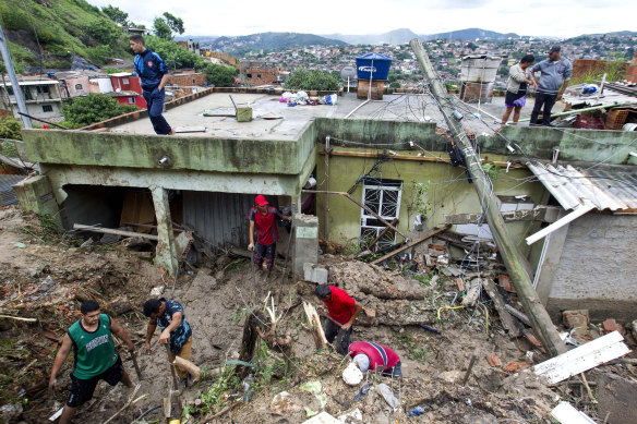 Locals work to clean up mud and debris around houses destroyed by a landslide after heavy rains in the Vila Ideal neighbourhood in Brazil. 