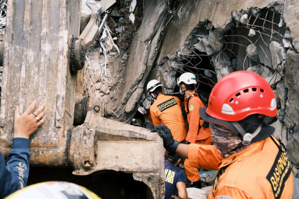 Rescuers search for victims at the ruin of a building damaged by an earthquake in Mamuju, West Sulawesi, Indonesia.