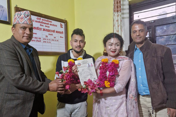 Same-sex couple Surendra Pandey, second left, and Maya Gurung, pose for a photograph with their marriage registration certificate at Dorje village council office in Kathmandu, Nepal.
