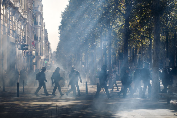 French riot police walk through a tear gas cloud on the Champs Elysees during the Yellow Vest demonstration on Saturday.