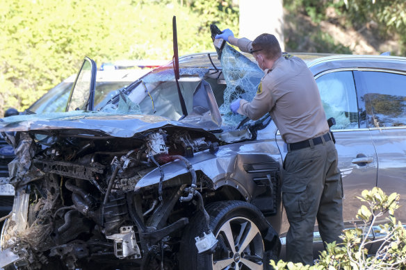 A police officer inspects Tiger Woods’ car after the golfer’s accident in February 2021.