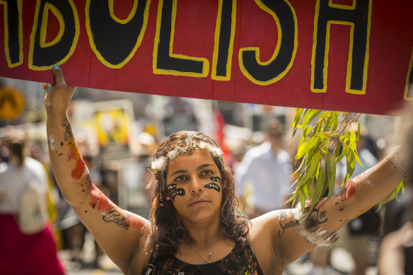 A woman at a 2019 Invasion Day march in Melbourne carries a sign calling for the abolition of Australia Day.