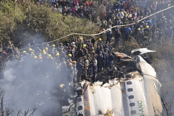 Nepalese rescue workers and civilians gather around the wreckage of a passenger plane that crashed in Pokhara, Nepal, on Sunday.