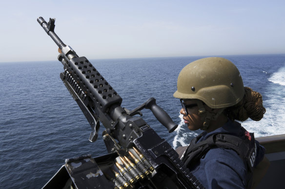 US Navy sailor stands guard next to a machine gun aboard the USS Paul Hamilton in the Strait of Hormuz.