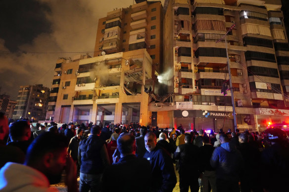 People gather outside a damaged building following a massive explosion in the southern Beirut suburb of Dahiyeh, Lebanon.