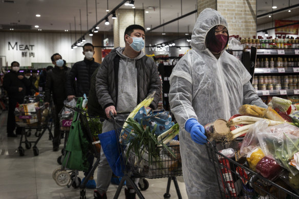 Chinese residents wear protective gear as they line up in a supermarket in Wuhan. 