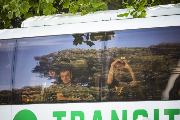 Mostafa "Moz" Azimitabar (right) makes a heart symbol as he is taken by bus away from the Park Hotel.