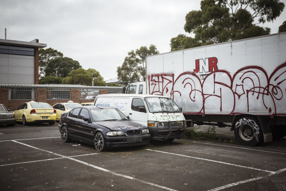 A truck, van and BMW sit in the the car graveyard.