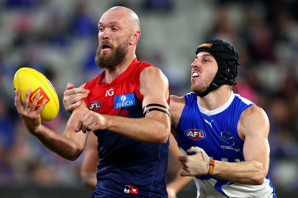 Max Gawn of the Demons handballs whilst being tackled by Tristan Xerri of the Kangaroos.