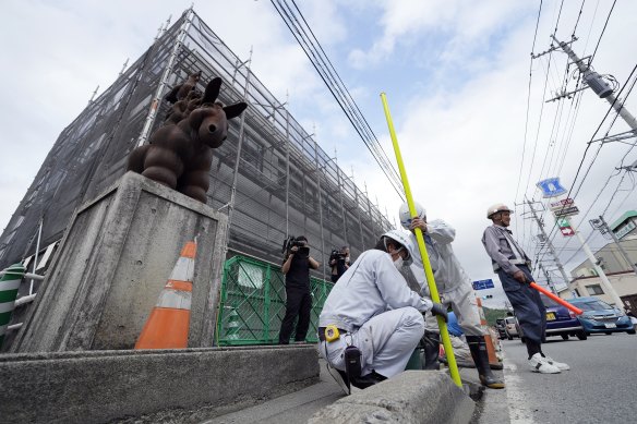 Workers set up a barricade near the Lawson convenience store to start construction of a wall to block the view.