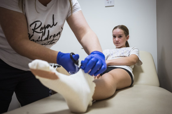 Violet Higgins, 12, has a dressing removed from her burned foot after making candied fruit in her home microwave.