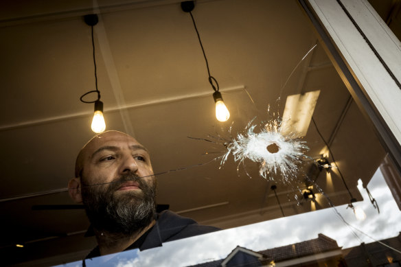 Cafe owner Fidel Takla surveys a bullet hole at his cafe. 