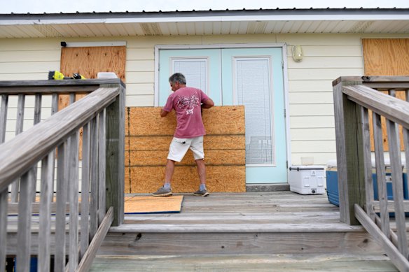 An Alabama resident boards up his home with plywood.
