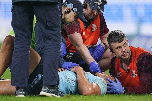 Joseph-Aukuso Suaalii is treated after a bad head knock on Friday night by Waratahs and Reds medical teams