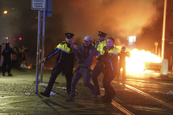 Irish police officers apprehend a man after a demonstration near the scene of an attack in Dublin.