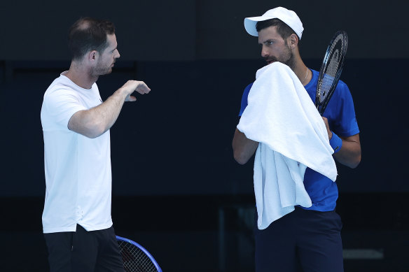 Andy Murray speaks to Novak Djokovic during a  practice session at Melbourne Park.