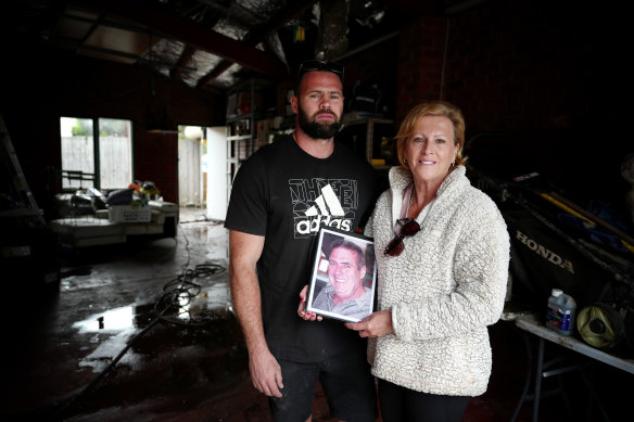 Tyson and Jane Trewin in Jane’s flooded home. Jane holds a photo of late husband Shane, who fought against the Flemington Racecourse flood wall.
