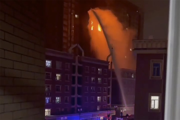 In this image taken from video, firefighters spray water on a fire at a residential building in Urumqi in western China’s Xinjiang region.
