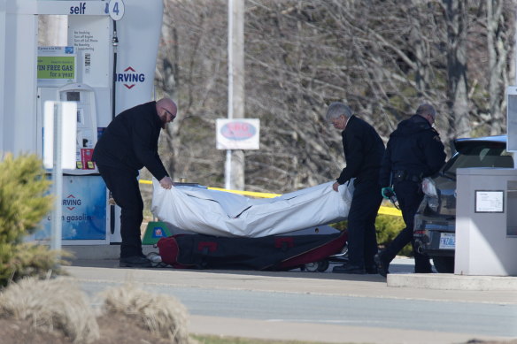 Workers with the medical examiner's office remove a body from a petrol station in Enfield, Nova Scotia, on Sunday.