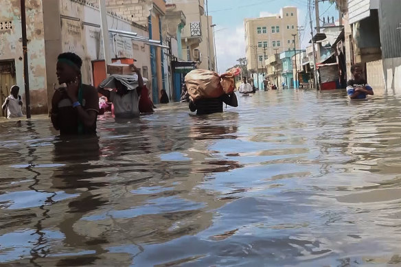 Men walk through floodwaters on a street in the town of Beledweyne, in Somalia.