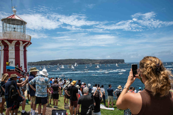 A crowd watches boats sail past the Hornby Lighthouse at South Head during the start of the Sydney to Hobart yacht race.