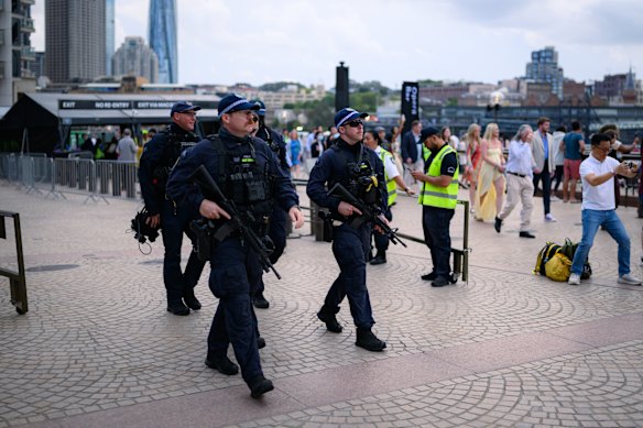 Police officers carry long-arm guns around the foreshore. 