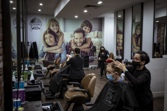 Sue Stallbaum with a client at the Cuts Only salon she manages at Northland, which had a queue of customers waiting when it opened on Tuesday.