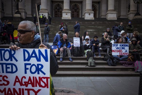 Demonstrators hold signs critical of Premier Daniel Andrews on Monday morning in the CBD.